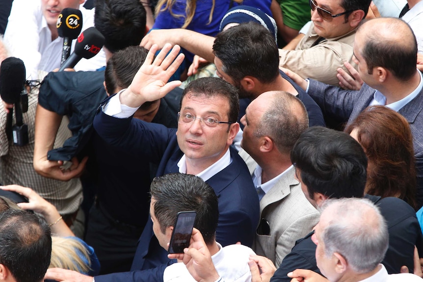 Ekrem Imamoglu waves and looks up from a crowd of people.