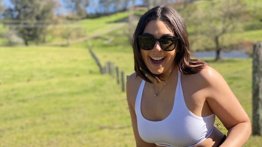 Smiling brown haired young woman in a park with a dog.