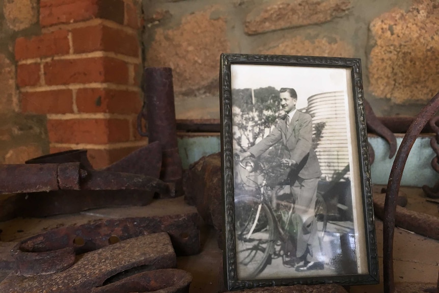 An old photo of world war 2 serviceman Lynn Parsons sits in a frame on a work bench.