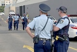 Police walking and standing at the site of a shooting in a Bankstown shopping centre car park.