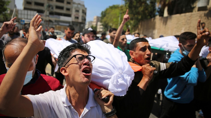 Mourners carry the the bodies of Palestinians who were killed in overnight Israeli airstrikes