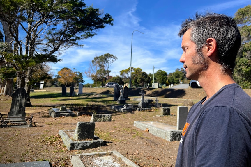 A man looks across a cemetery.