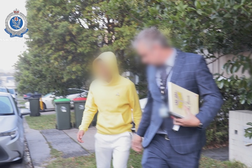 a man wearing a hoodie with his face blurred out in the picture is arrested in south coogee by police