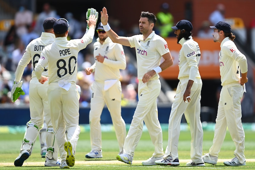 Jimmy Anderson high-fives Jos Buttler as the England team gather together