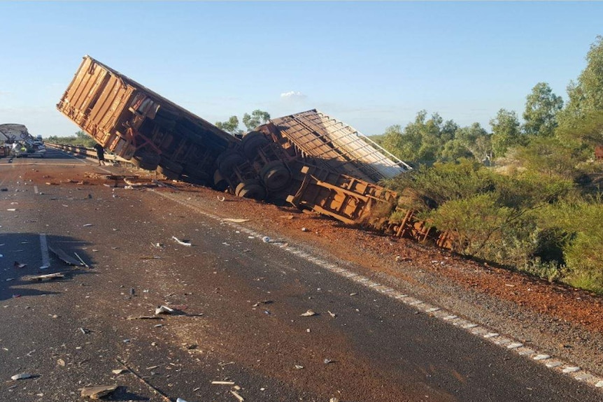 A cattle truck crumpled and lying among debris from a road accident
