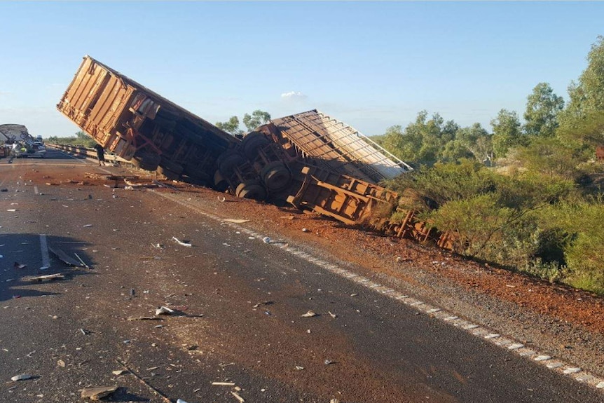 Debris from a road accident, a truck is crumpled by the side of the road.