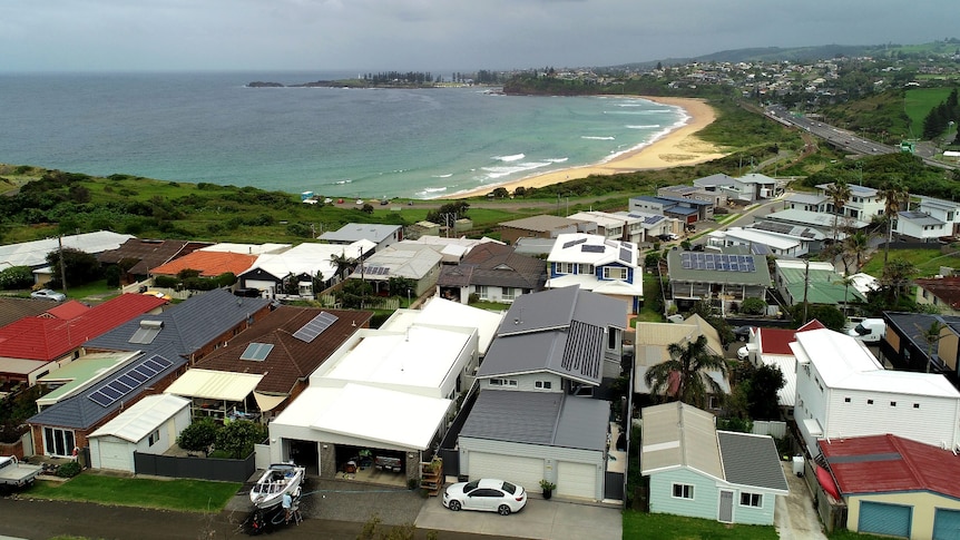 An overhead photo of houses on a headland adjacent the ocean