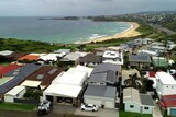 An overhead photo of houses on a headland adjacent the ocean