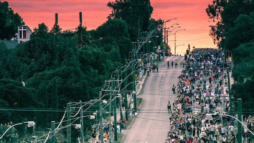 Crowds gather along Canning Highway for a festival at sunset