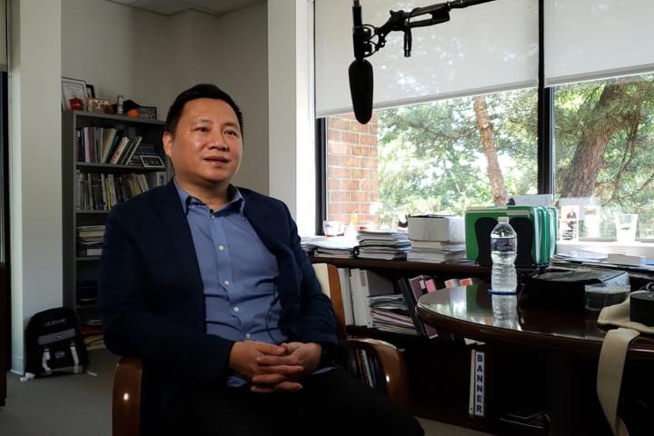 A Chinese man speaking into a microphone. 