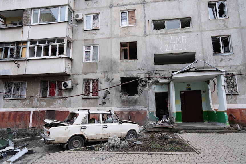 A damaged car sits out the front of a damaged residential building in Mariupol, Ukraine.