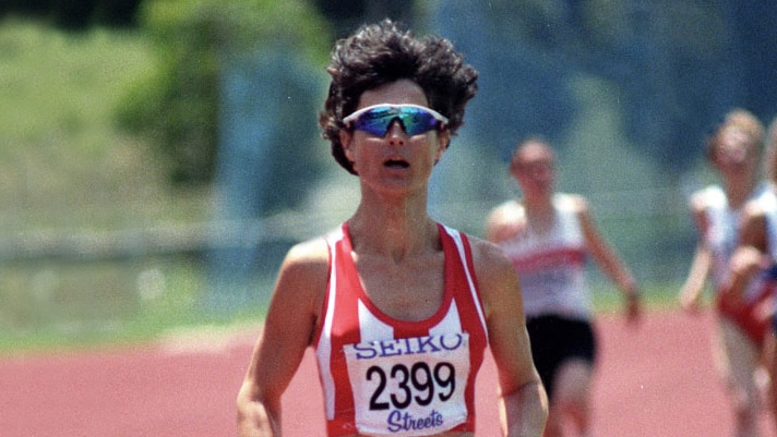 A woman runs down an athletics track.