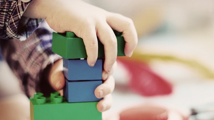 Unidentified child's hands playing with building bricks.