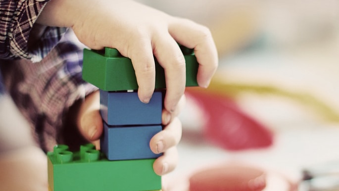 Unidentified child's hands playing with building bricks.