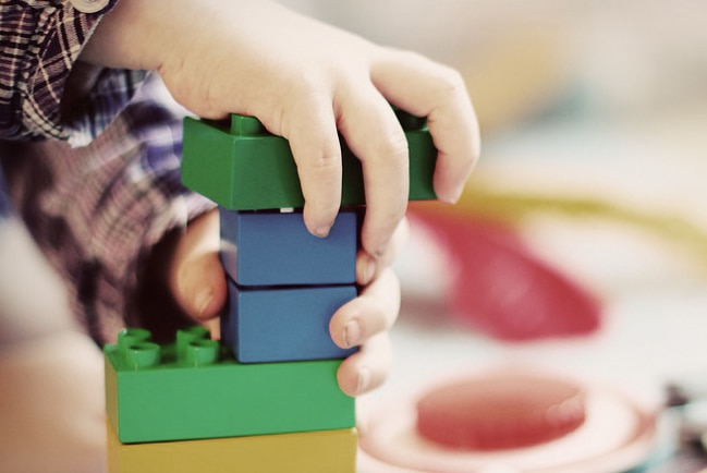 The hands of an unidentified child playing with building bricks.
