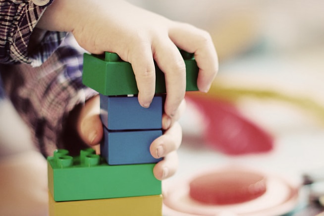 Unidentified child's hands playing with Lego.