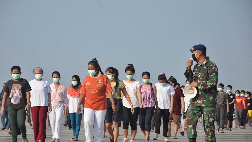 Indonesian migrant workers who arrived from Malaysia exercise during quarantine.