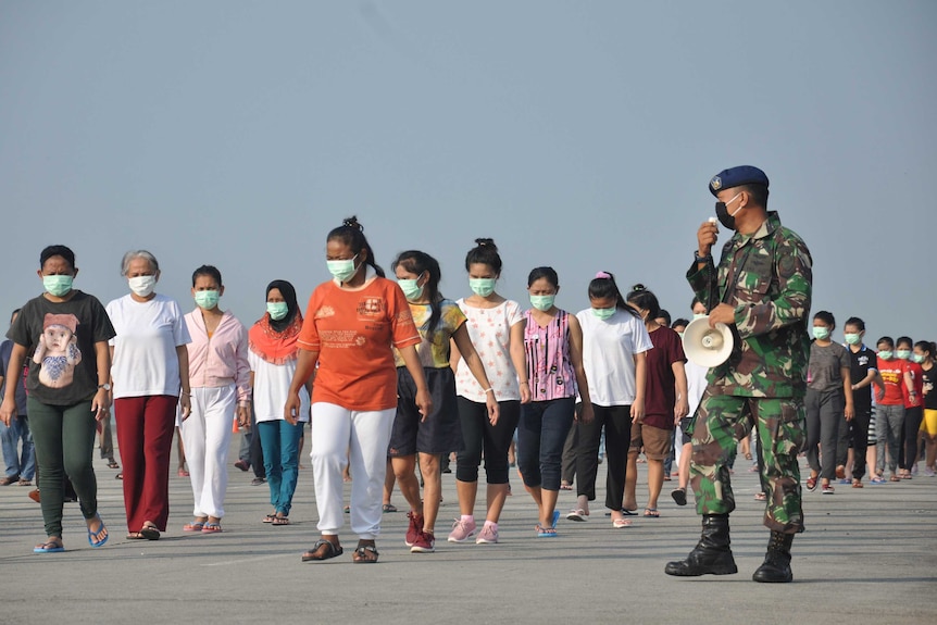 Indonesian migrant workers who arrived from Malaysia exercise during quarantine.