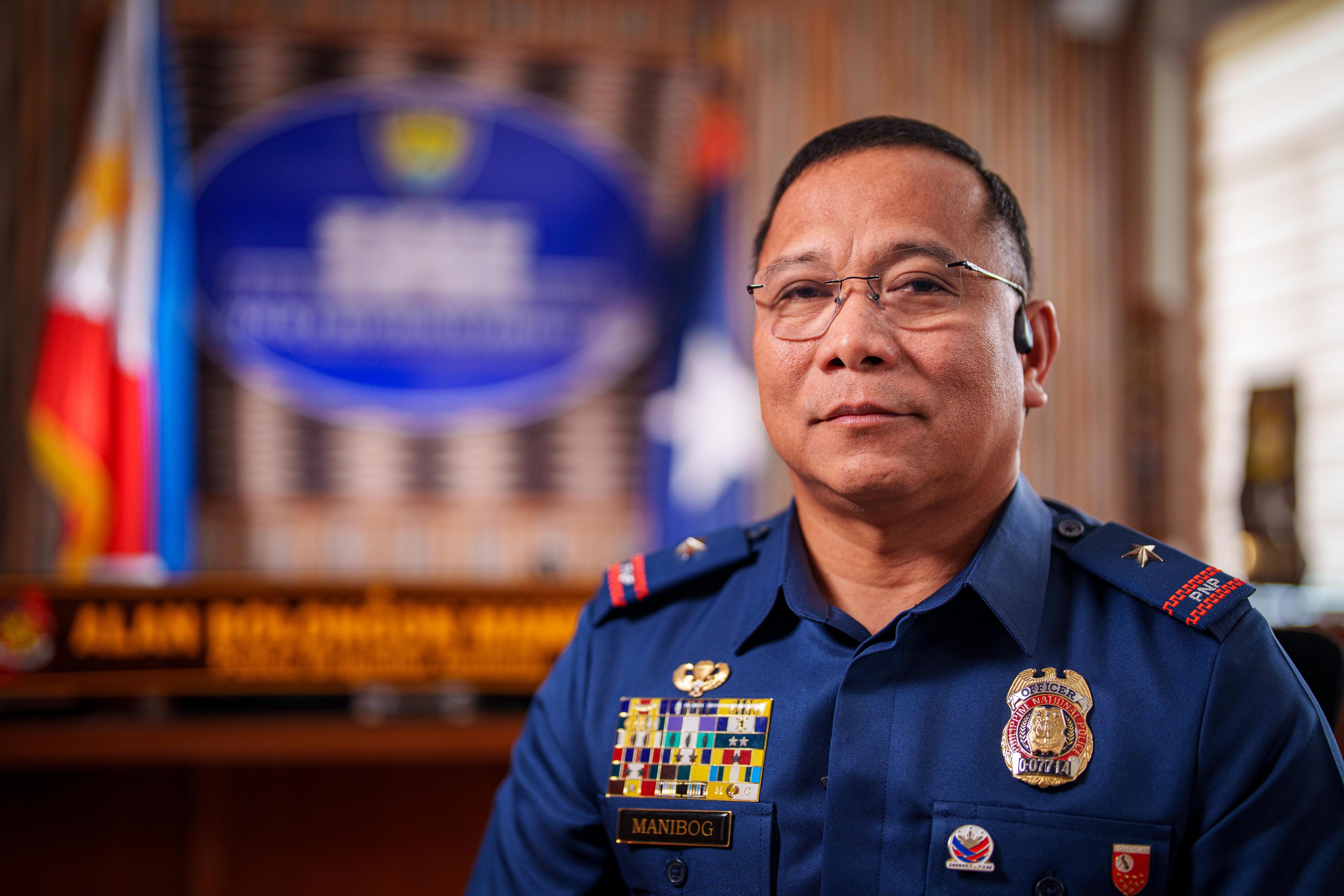 A middle-aged Filipino man with short hair and glasses wearing the Philippines National Police uniform in an ornate office.