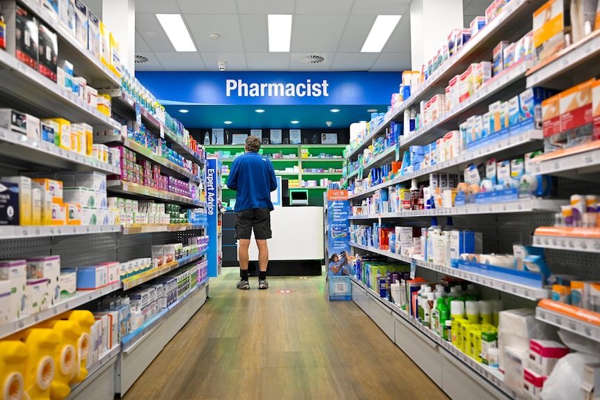 a male customer stands waiting at a pharmacy counter