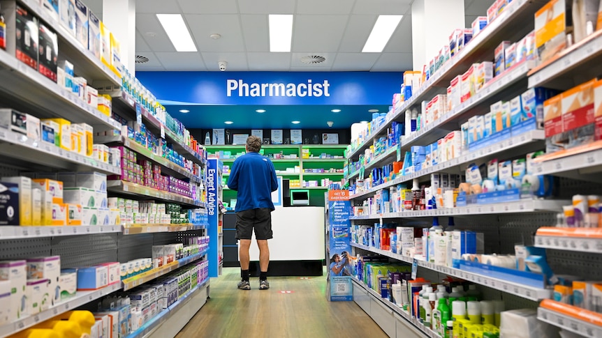 a male customer stands waiting at a pharmacy counter