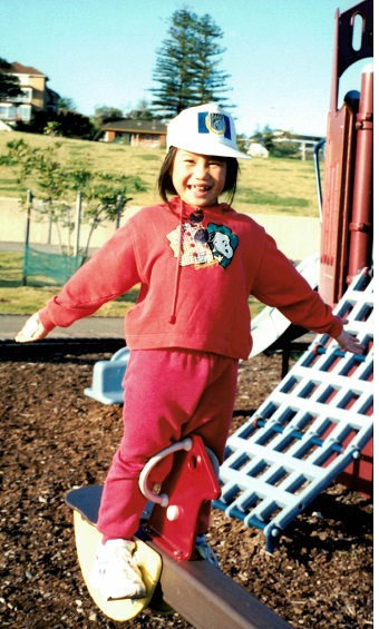 A young girl laughs at the camera while playing at the local park.