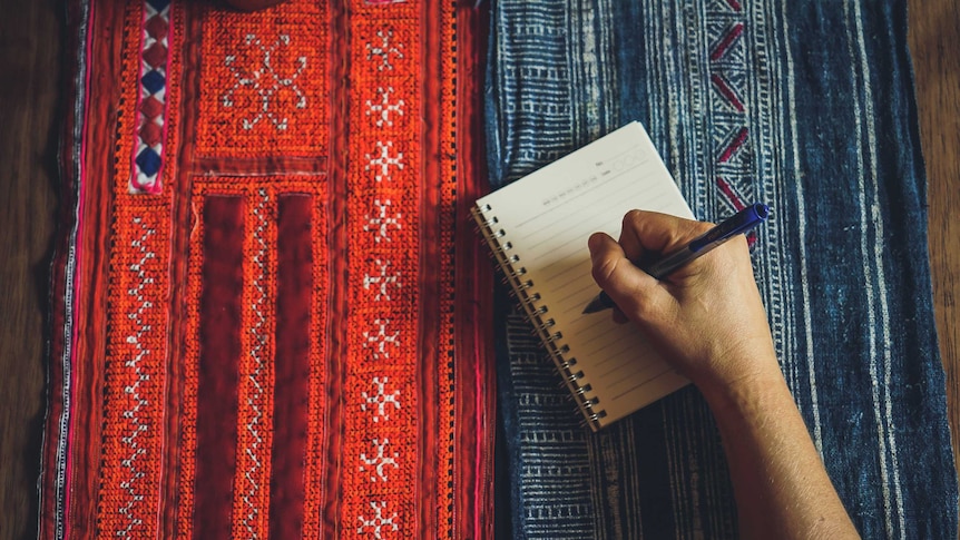 A person's hand with a pen about to write on a book