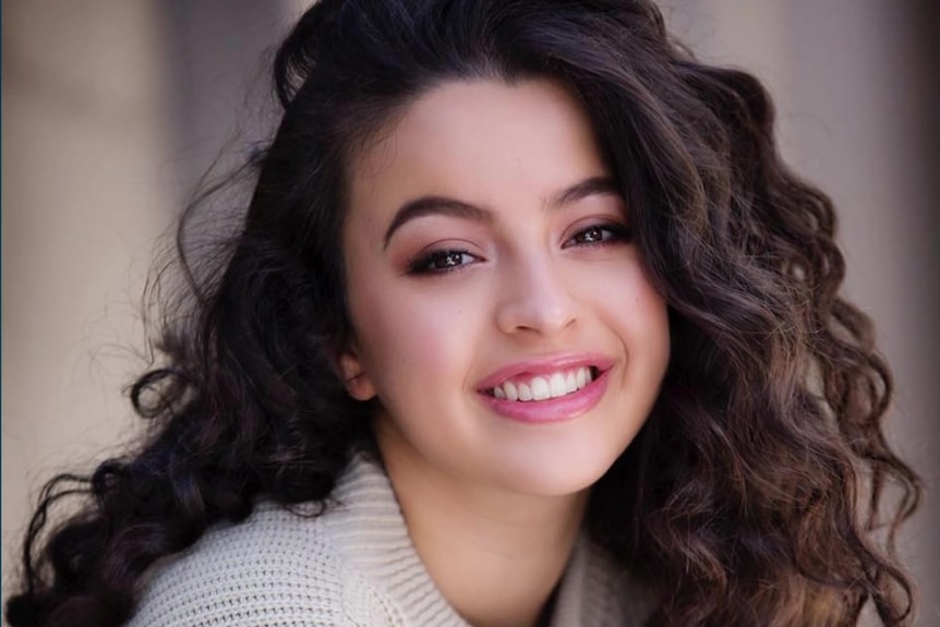 A young woman with wavy hair smiles