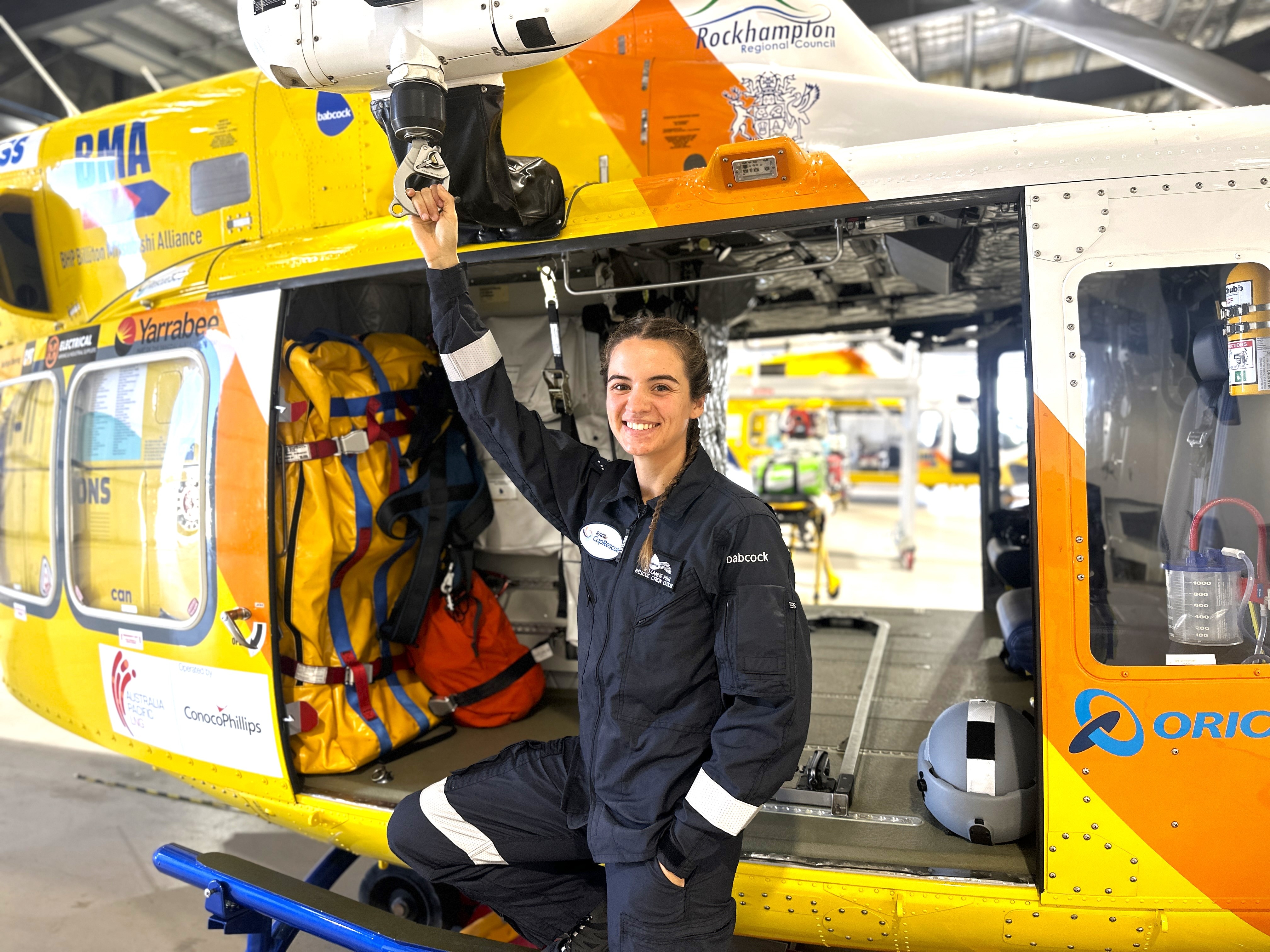 A young woman with dark hair near a helicopter wearing a navy aviation uniform.