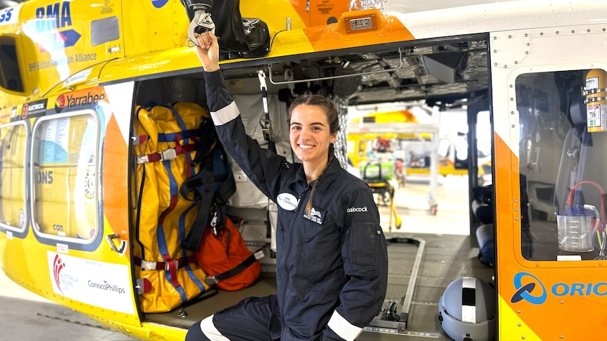 A young woman with dark hair near a helicopter wearing a navy aviation uniform.