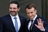 Lebanon's Prime Minister Saad Hariri is standing next to French President Emmanuel Macron, who is waving.