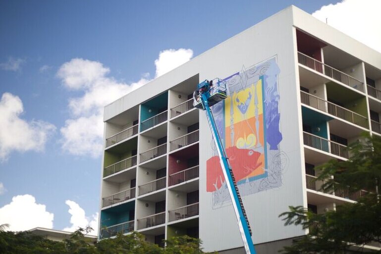 Man on cherry picker painting the side of a hotel in Cairns