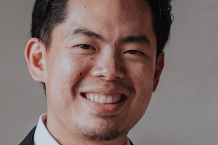 Close up of a young man with dark hair smiling at the camera