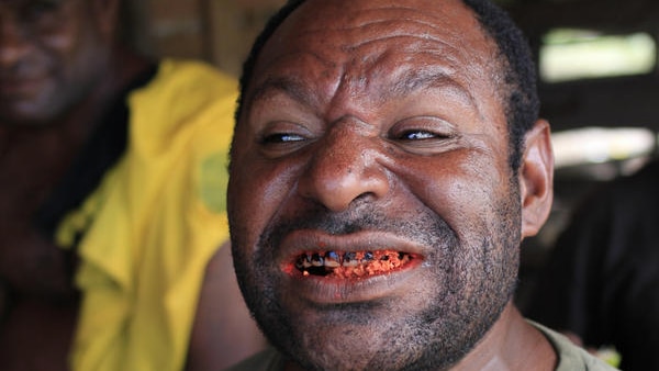 A PNG man shows his red stained teeth.