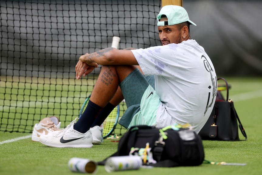 Nick Kyrgios looks over his shoulder as he sits on a practice court at Wimbledon.