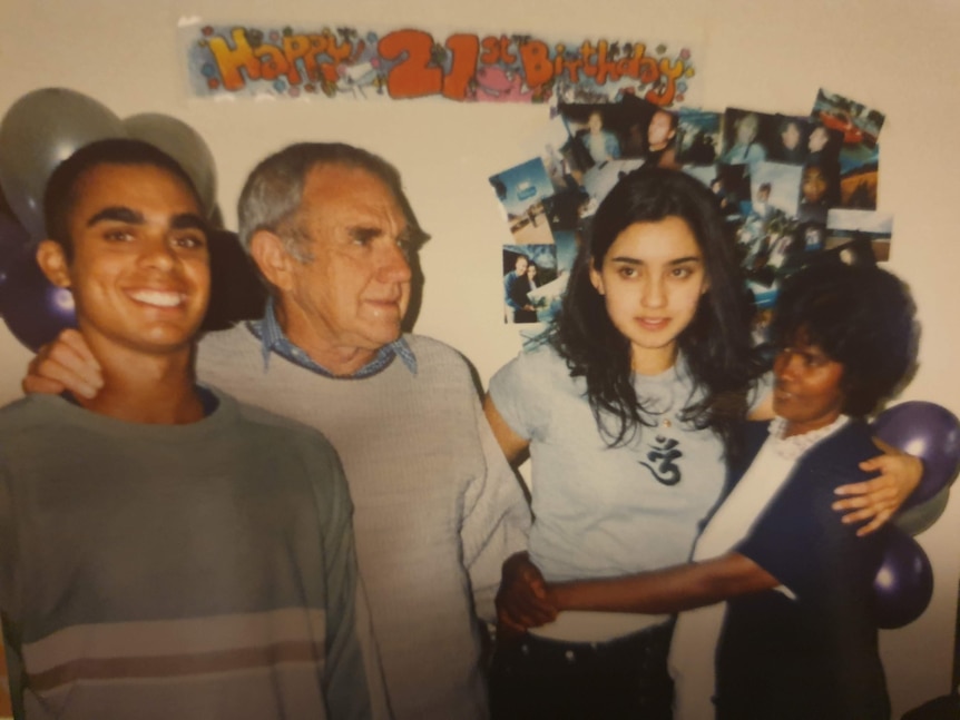 An older couple with two young people with a 21st birthday banner behind