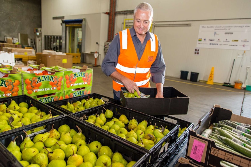 Foodbank Victoria chief executive Dave McNamara puts pears in a box.