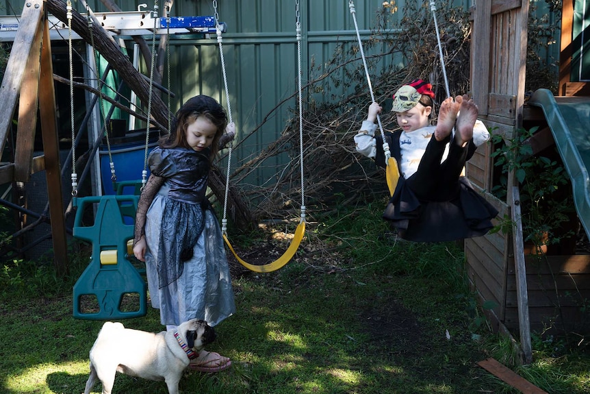 Israel and Miette playing on a swing set in their backyard.