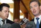LtoR Nick Xenophon stares intently at Christopher Pyne as Mr Pyne speaks at a press conference.