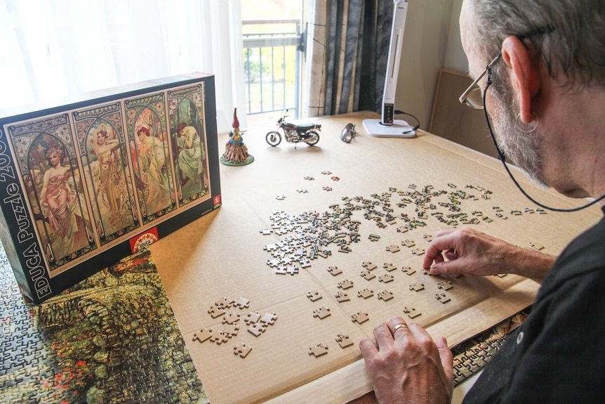 A man studies a jigsaw puzzle piece looking to identify features
