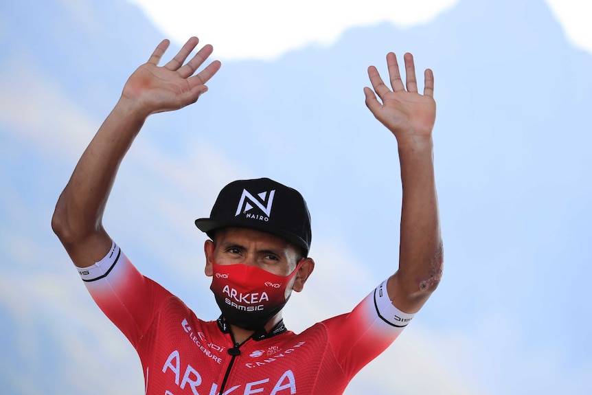 Nairo Quintana waves to the crowd wearing a red and black mask