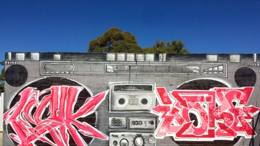Spray-painted street art of an 80s style cassette player and colours in red, grey and black.