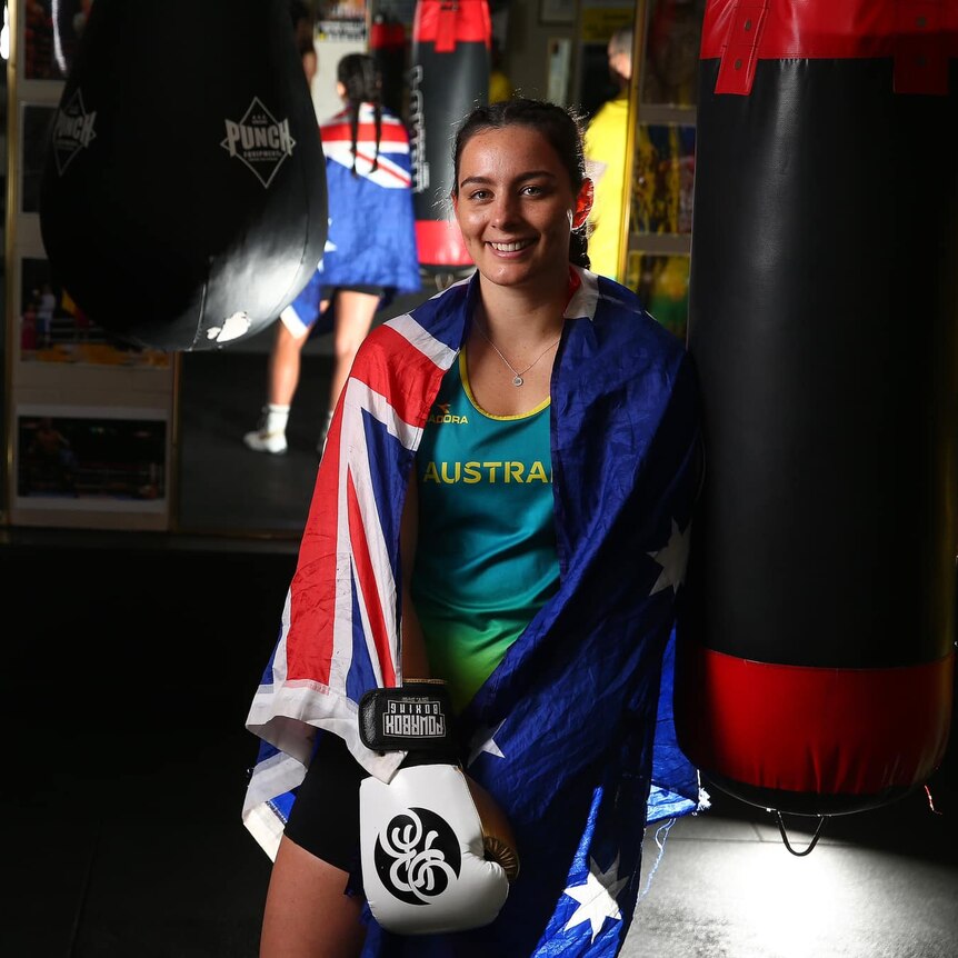woman sits with Australian flag around shoulders in a boxing ring