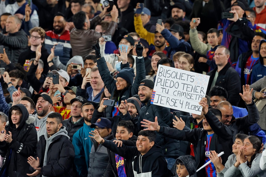 Fans at a soccer match hold up a sign during a match in Australia