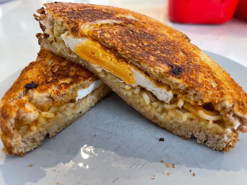 A well cooked toastie, filled with fried egg and noodles.