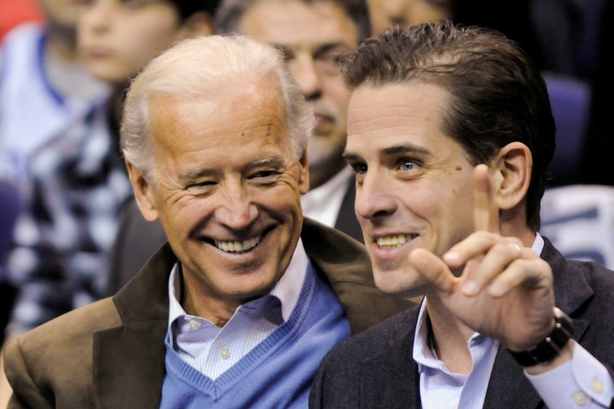 A older man smiles while looking at a younger man. Joe Biden (left) with his son Hunter (right).