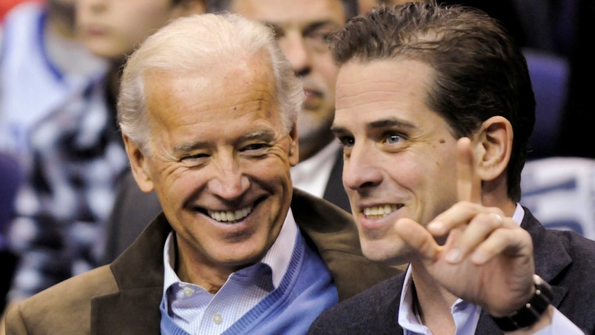 A older man smiles while looking at a younger man. Joe Biden (left) with his son Hunter (right).