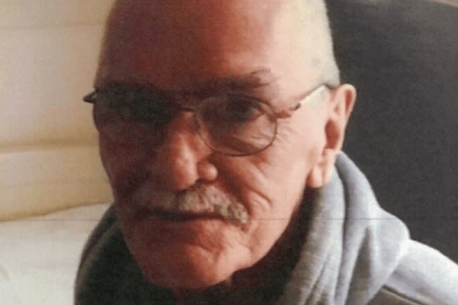 An older, balding man with a white moustache and glasses.