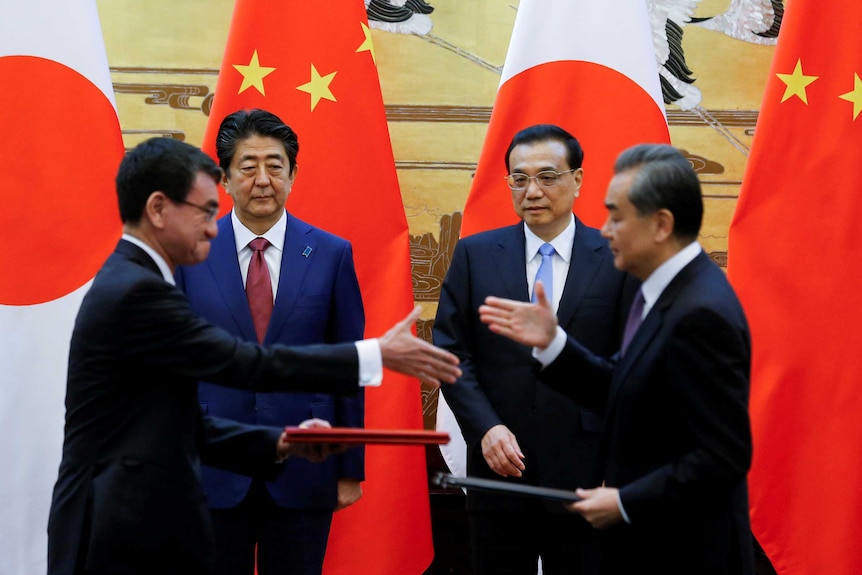 I leader di Cina e Giappone si stringono la mano davanti alle grandi bandiere dei loro paesi