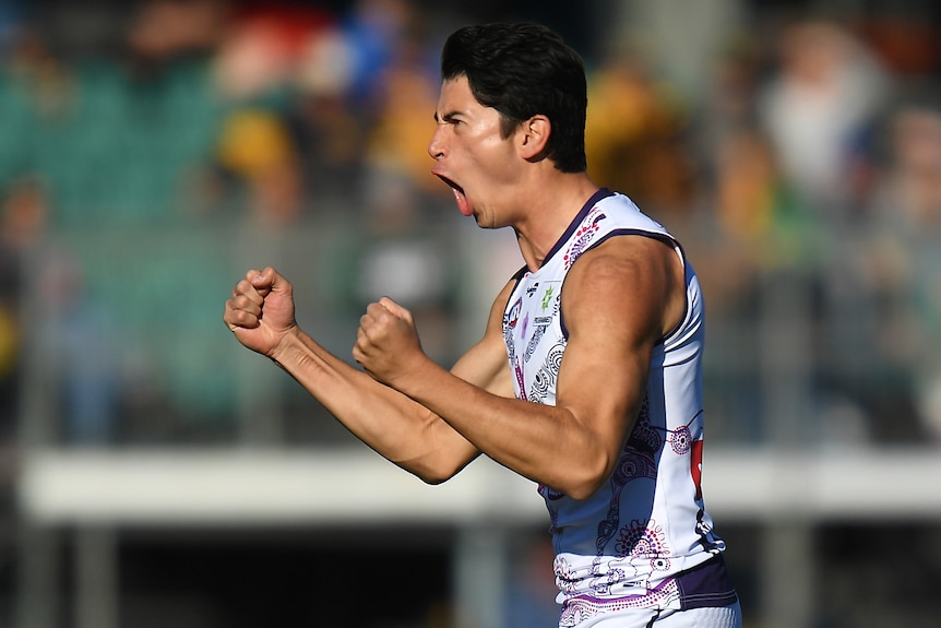 A Fremantle AFL player pumps both his fists as he celebrates kicking a goal against Hawthorn.